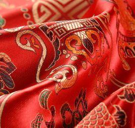 Látka brokát červeným se zlatým orientálním motivem 